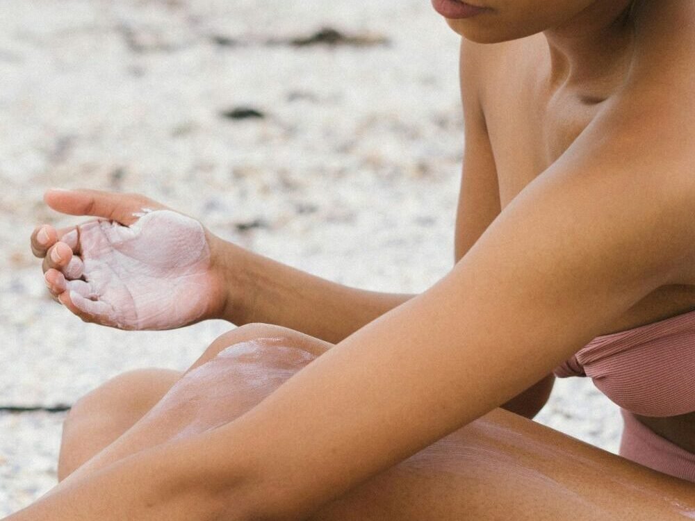  mulher  cuidando da pele passando protetor solar para tomar sol. 