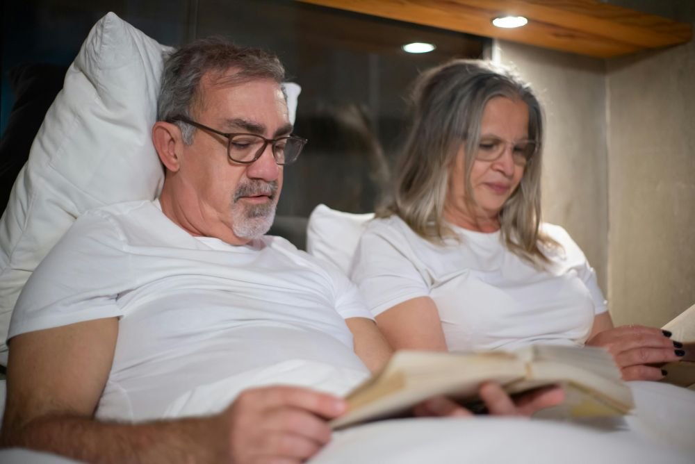 mulher madura e seu esposo, lendo na cama antes de dormir
