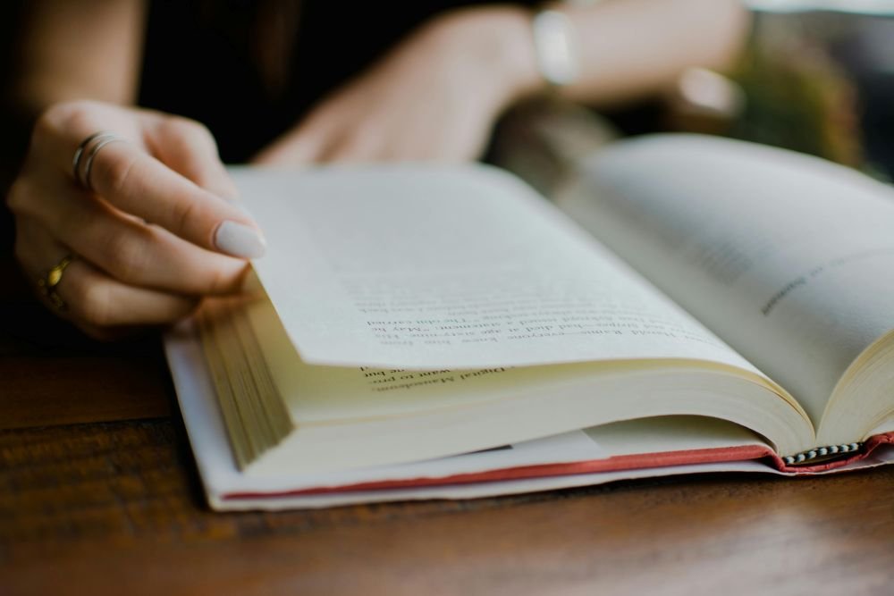 mulher foleando pagina do livro físico que está lendo