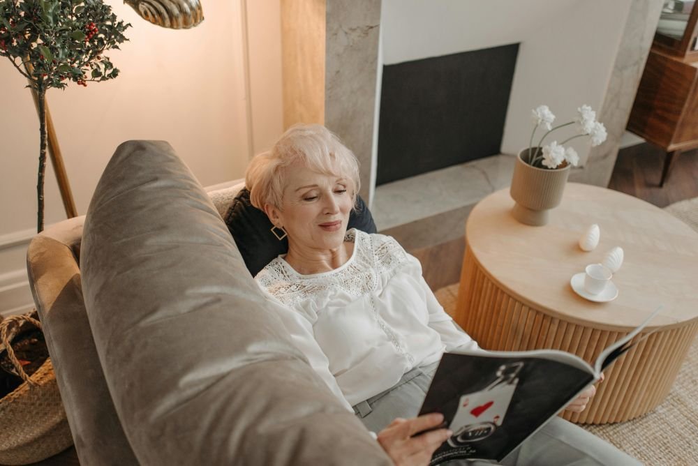 mulher madura descansando no sofá enquanto lê uma revista