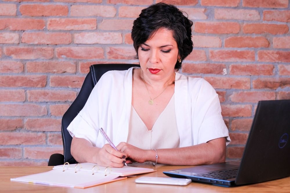 mulher madura anotando  em sua agenda, fatos importantes observados em sua leitura anterior, isso a ajudará o cérebro manter-se mais atento e a entender melhor o que lê