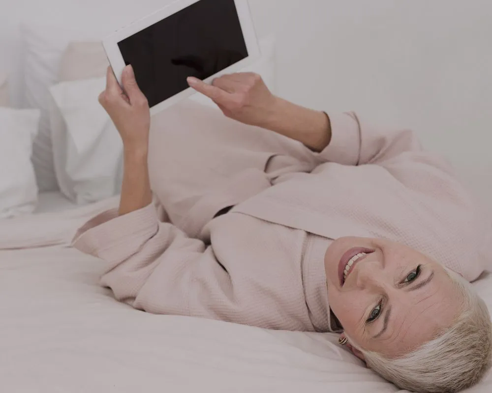 mulher deitada na cama lendo no tablet