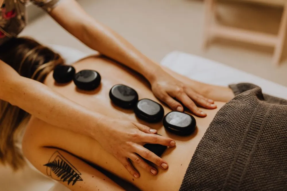 Massoterapia Integrativa, com pedras realizada em mulher em menopausa para aliviar dores lombar
