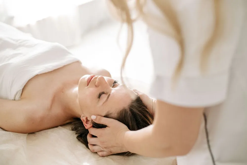 Massagem baseada em neurociência, mulher deitada recebendo massagem na cabeça e pescoço para aliviar tenção e ansiedade