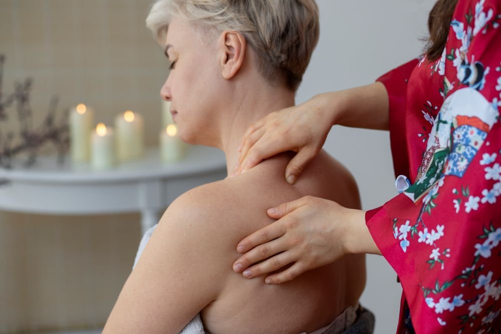 mulher madura, em menopausa, sentada recebendo massagem relaxante na costa para aliviar o estresse